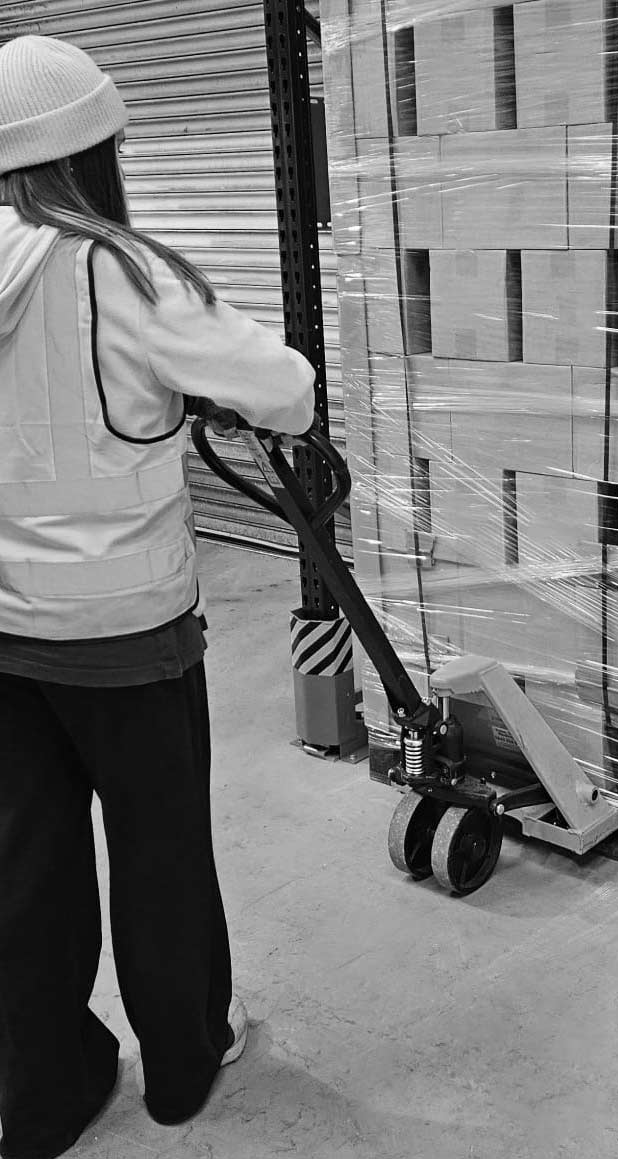 Person using a pallet jack in a warehouse setting