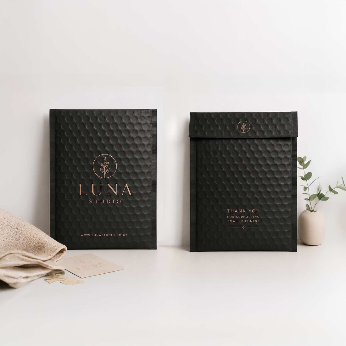 Two black textured envelopes with 'Luna Studio' branding on a white surface.