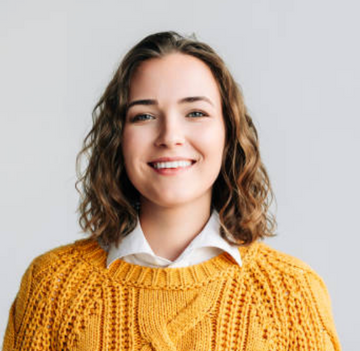 Woman wearing a yellow sweater with a plain background
