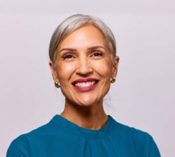 Woman with gray hair wearing a blue top against a light gray background