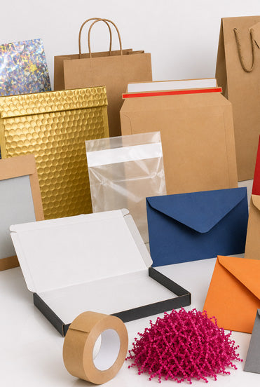 Collection of various packaging items including bags, boxes, and tape on a white surface.