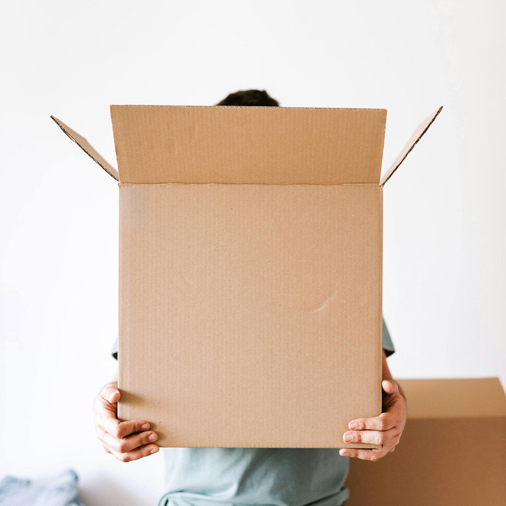 Person holding a cardboard box against a white background