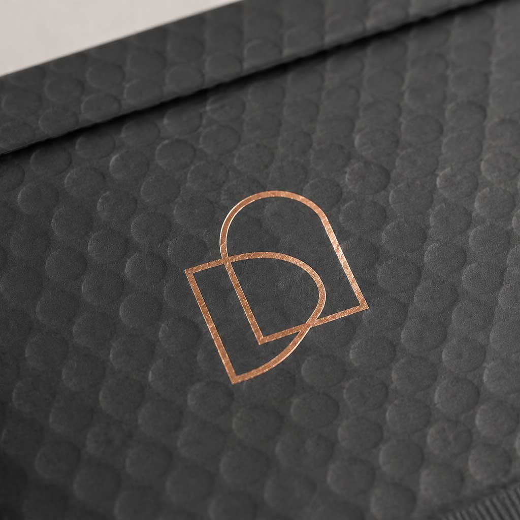 Close-up of a textured black surface with a rose gold logo.